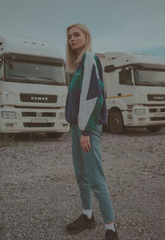a woman standing in front of a line of trucks, an album cover, by Attila Meszlenyi, casual streetwear, green and blue tones, anastasia ovchinnikova, low quality photo