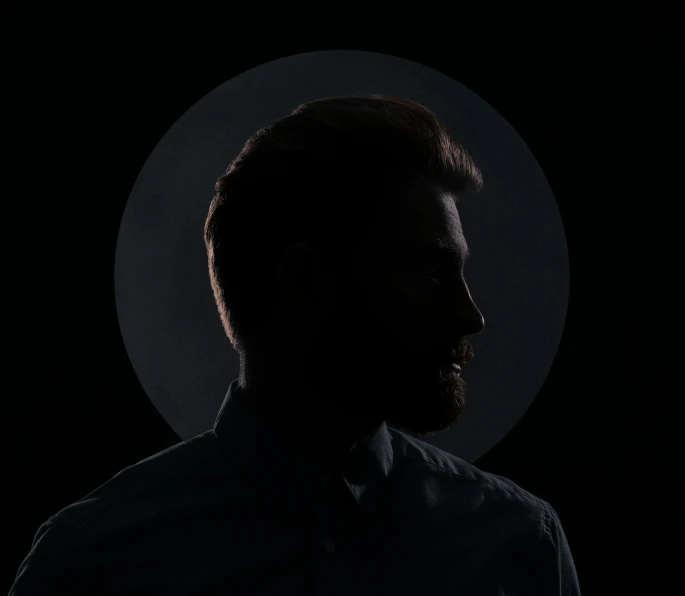 a man with a beard in a dark room, an album cover, by Leo Leuppi, unsplash, minimalism, moon backlight, dustin lefevre, clear silhouette, ignant