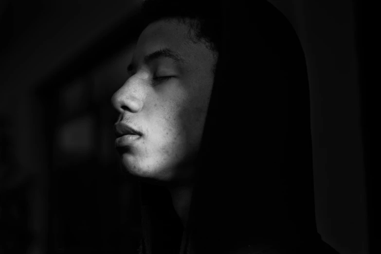 a black and white photo of a man with his eyes closed, pexels contest winner, realism, black teenage boy, face is brightly lit, african american woman, black hood