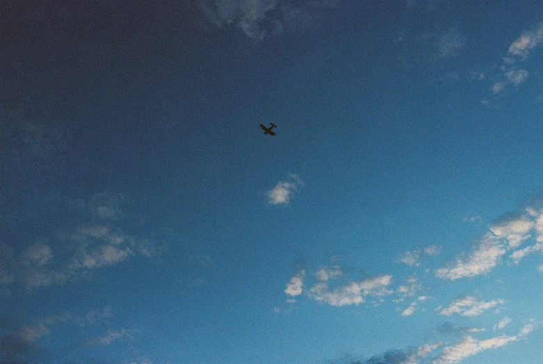 a plane flying through a cloudy blue sky, by Attila Meszlenyi, postminimalism, lo fi, william eggleston, 35mm —w 1920 —h 1080, ariel perez