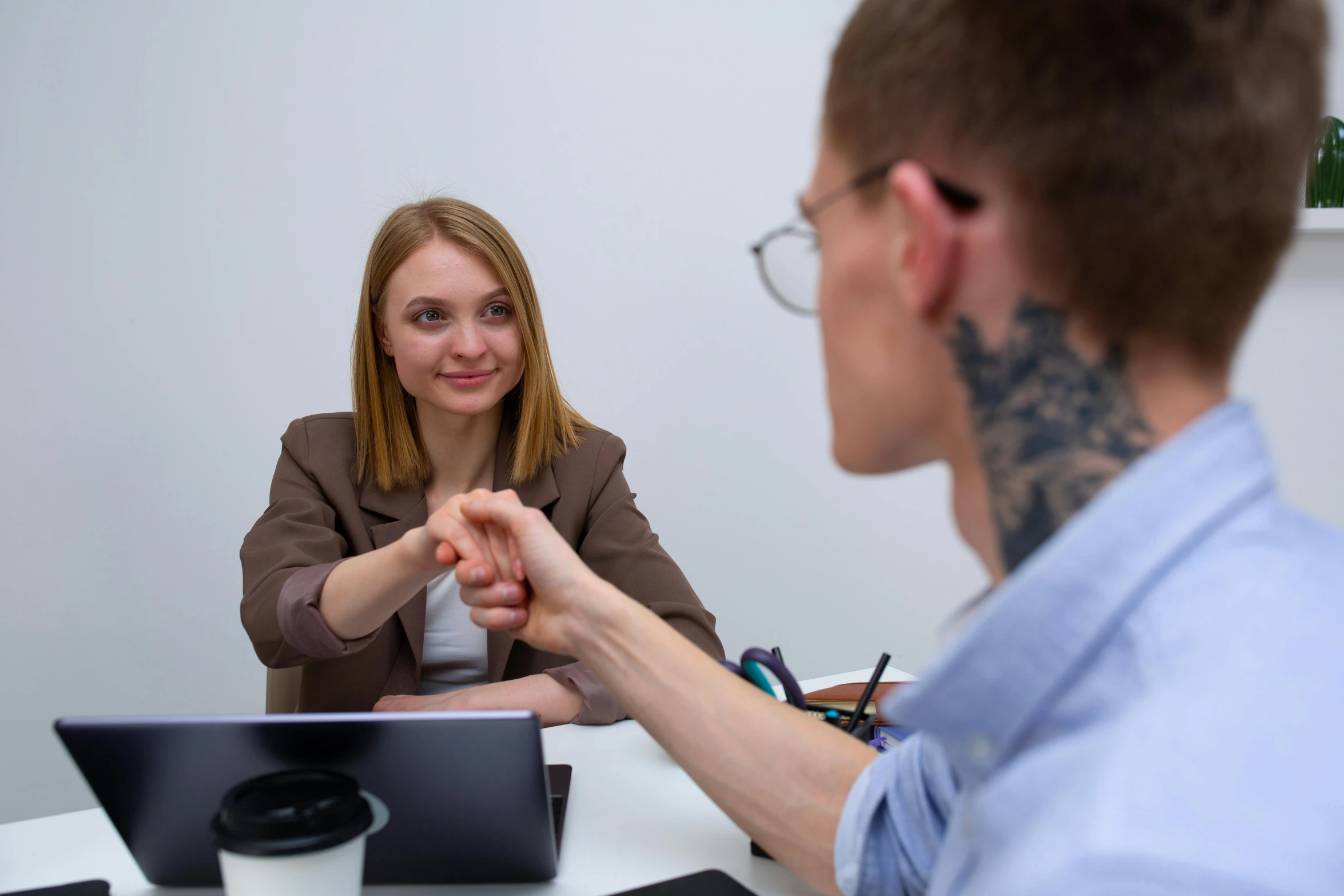 a man and a woman sitting at a table, by Adam Marczyński, pexels contest winner, shaking hands, low quality photo, in the office, thumbnail