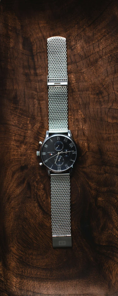 a watch sitting on top of a wooden table, a portrait, by Tom Bonson, pexels contest winner, modernism, crosshatch, gunmetal grey, icon, instagram post
