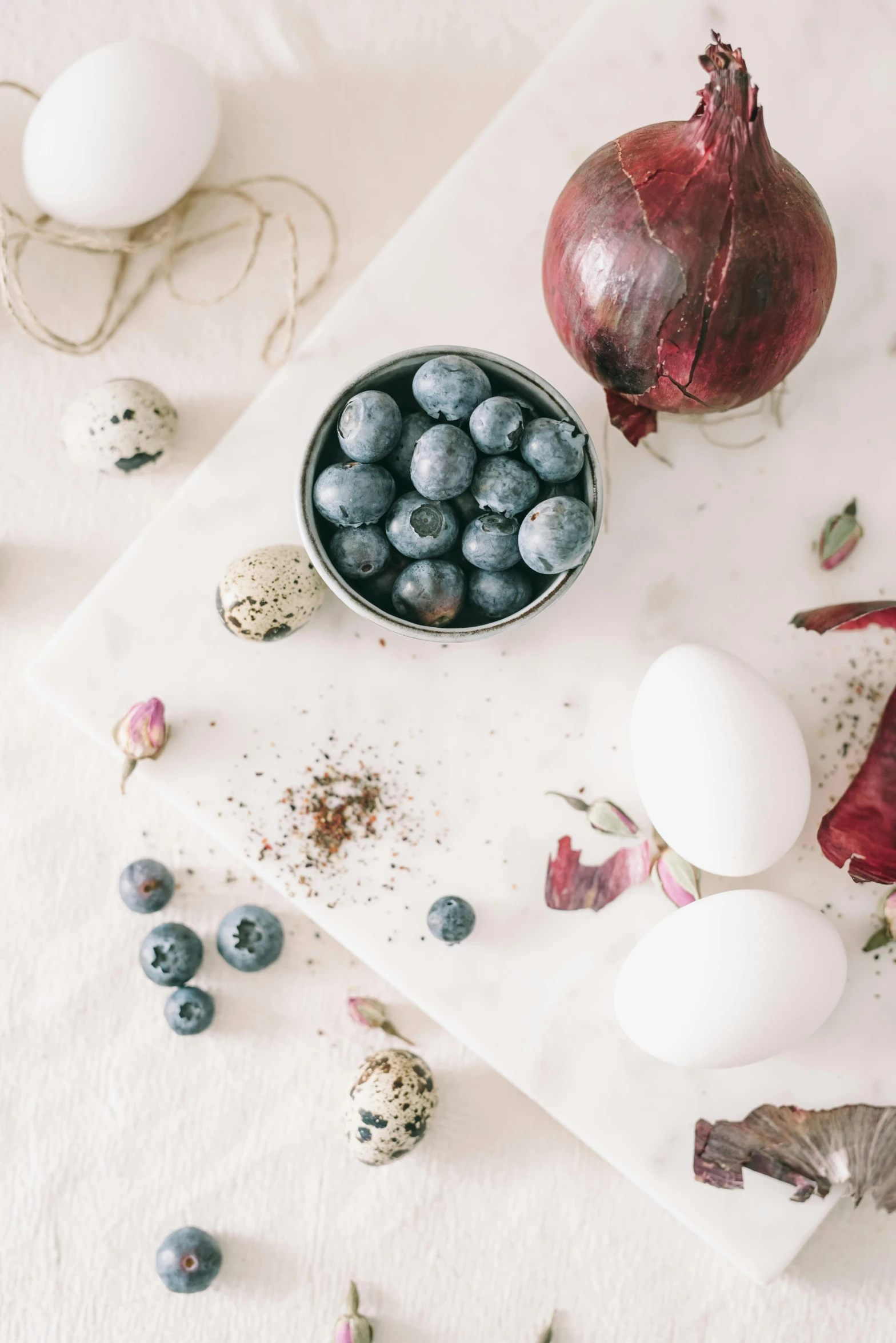 a table topped with eggs, blueberries, and pomegranates, a still life, trending on pexels, white, grape hyacinth, grey, banner