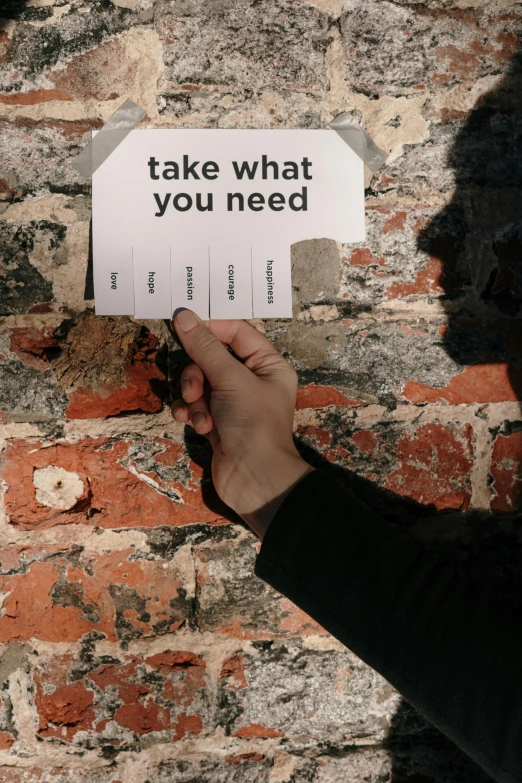 a person holding a sign that says take what you need, unsplash, conceptual art, brick walls, labels, vito acconci, declan mckenna