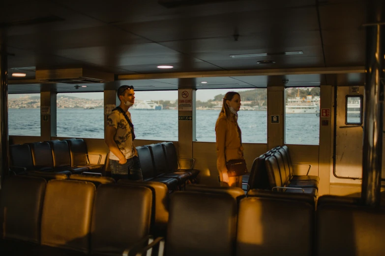 a couple of men standing next to each other on a boat, by Elsa Bleda, pexels contest winner, serial art, interior of staten island ferry, moody : : wes anderson, sun behind her, cinema still