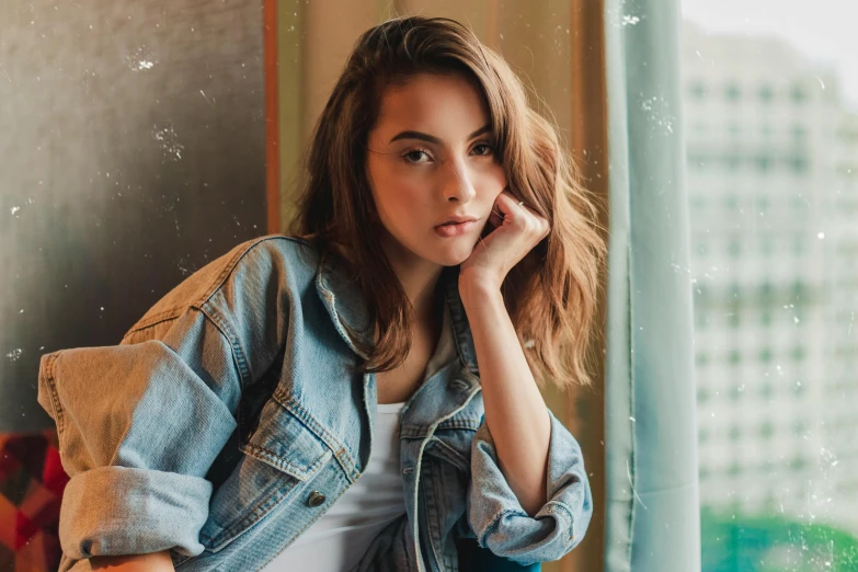 a beautiful young woman sitting next to a window, trending on pexels, photorealism, jean jacket, pokimane, confident pose, promo image