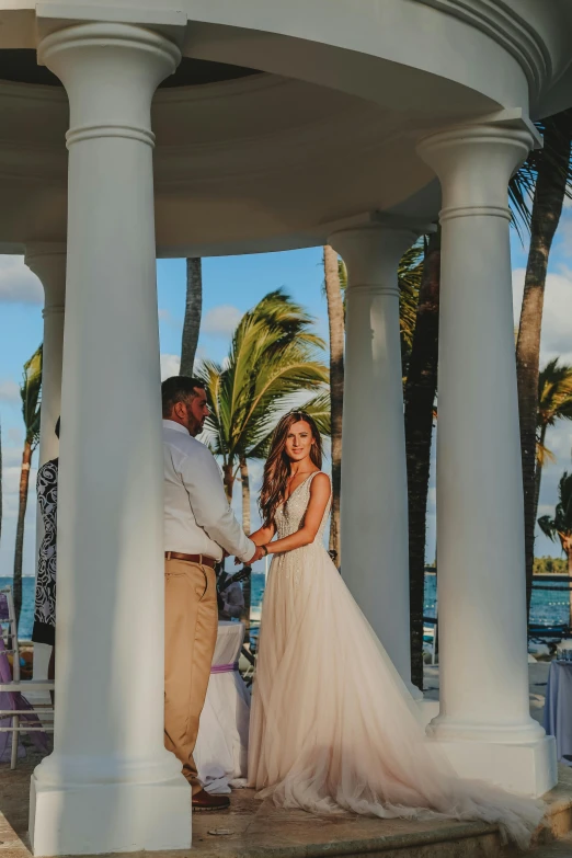 a man and a woman standing under a gazebo, by Robbie Trevino, palm trees in the background, luxurious wedding, slide show, barcelo tomas