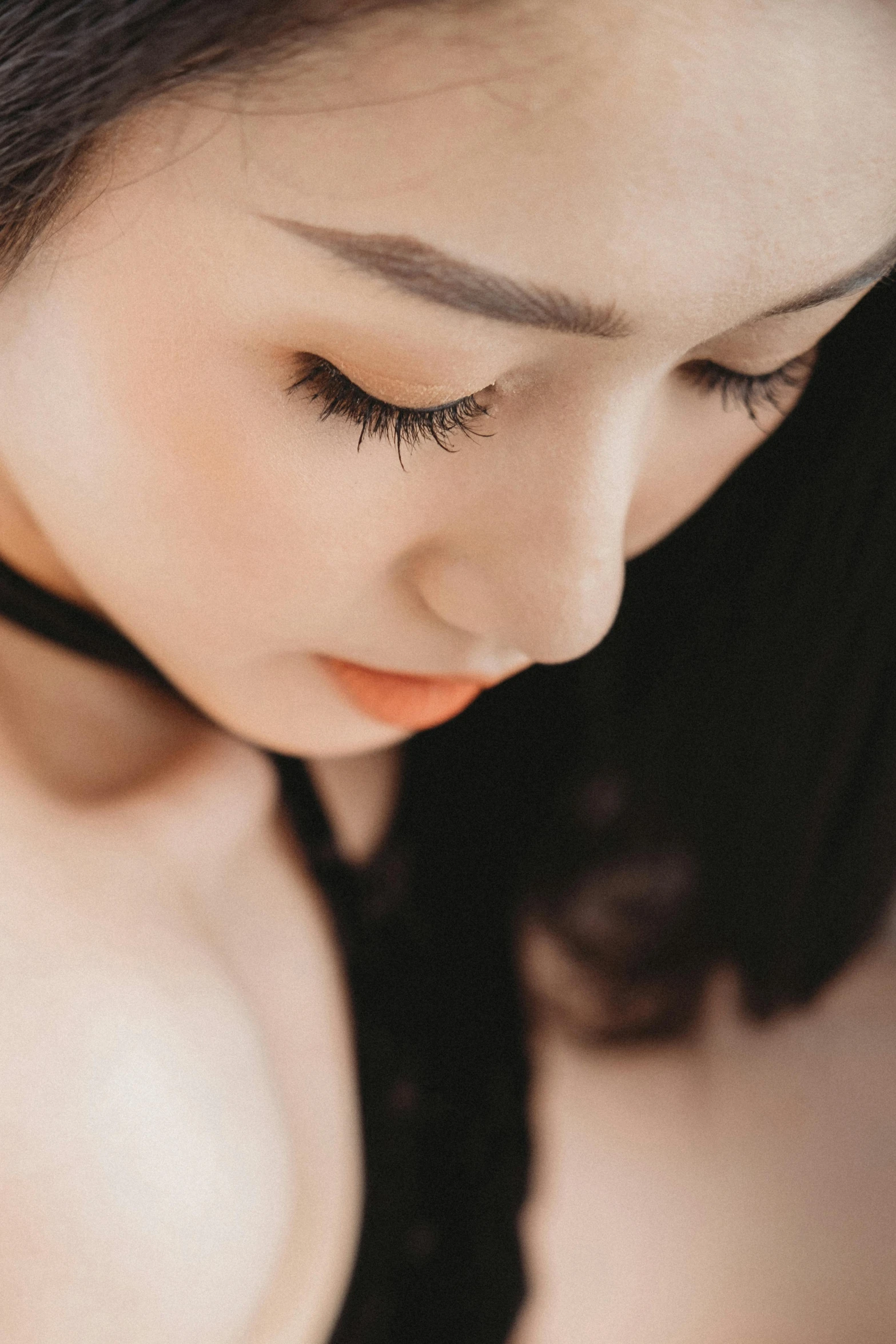 a close up of a woman wearing a black dress, inspired by Ruth Jên, trending on pexels, eyes half closed, asian girl, skincare, pale woman