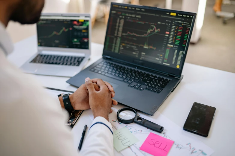 a man sitting at a desk with two laptops, trending on pexels, analytical art, car trading game, mathematical, thumbnail, holding close