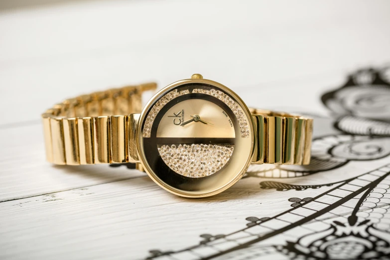 a close up of a wrist watch on a table, an album cover, by Julia Pishtar, gold and gems, curvy build, detailed product photo, demur