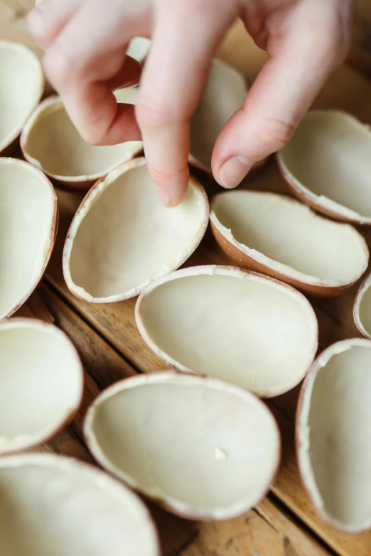 a close up of a person putting something in a bowl, by Jessie Algie, dragon eggs, in rows, vanilla, dezeen