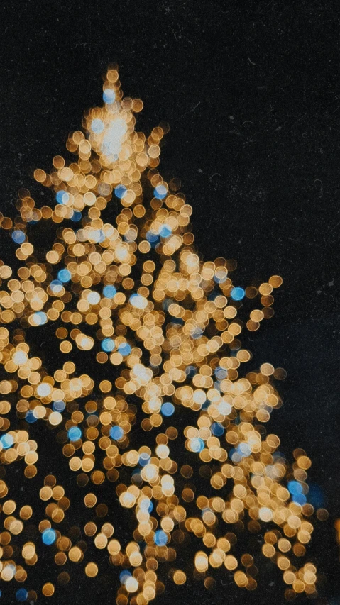 a christmas tree is lit up in the dark, an album cover, by Attila Meszlenyi, pexels, pointillism, high angle close up shot, golden light film grain, blue, on a gray background