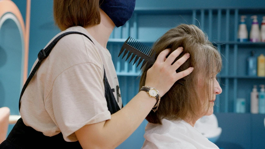 a woman combing another woman's hair in a salon, by Julia Pishtar, trending on pexels, no face mask, thumbnail, still frame, half - length photo