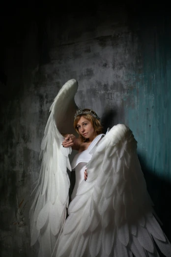 a woman dressed as an angel poses for a picture, an album cover, inspired by Cindy Sherman, pexels contest winner, renaissance, dark backdrop, in white room, portrait shot 8 k, tattered wings