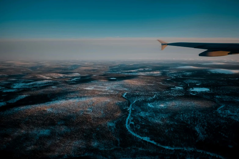the wing of an airplane flying over a snowy landscape, by Christen Dalsgaard, pexels contest winner, hurufiyya, overlooking a vast serene forest, late evening, thumbnail, waterfalls in distance