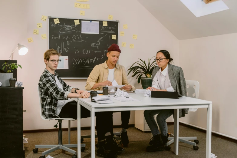 a group of people sitting around a white table, on a desk