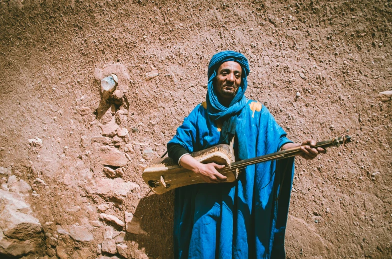 a man in a blue robe holding a guitar, pexels contest winner, les nabis, tuareg, 1970s photo, 🤠 using a 🖥, tourist photo