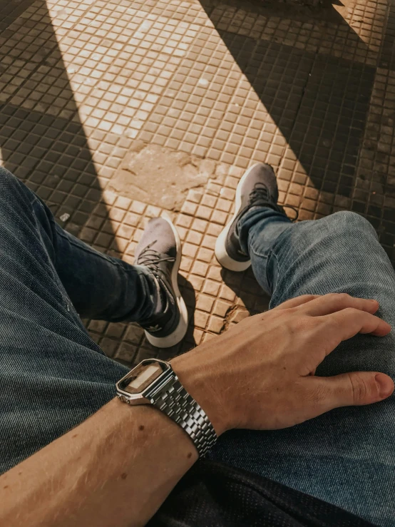 a person sitting on the ground holding a cell phone, by Pablo Rey, trending on pexels, hyperrealism, wears a watch, wearing two silver bracelets, childhood friend vibes, strong contrasting shadows