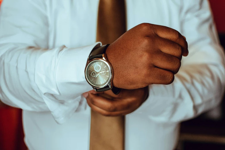 a close up of a person wearing a watch, by Adam Marczyński, pexels contest winner, formal attire, thumbnail, man is with black skin, wearing a white button up shirt