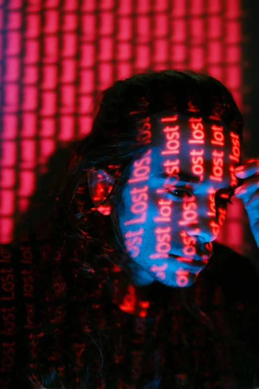 a woman holding a cell phone to her ear, a hologram, pexels, ascii art, red and blue black light, lost in code, red mesh in the facede, spy