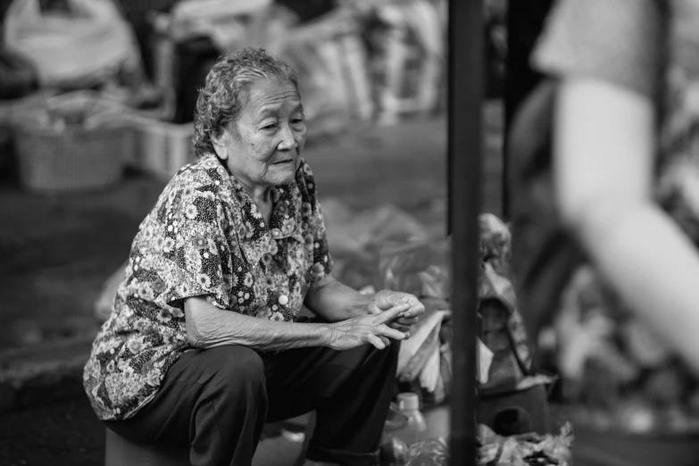 a black and white photo of a woman sitting on the ground, by Joze Ciuha, pexels contest winner, bangkok townsquare, grandma, vendors, 8k 50mm iso 10