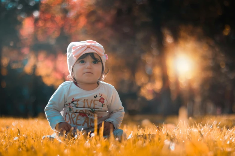 a baby sitting on top of a lush green field, by Lilia Alvarado, pexels contest winner, autumn sunlights, avatar image, blank, low - angle shot