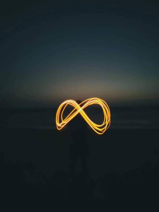 a person standing on top of a beach at night, inspired by Bruce Nauman, pexels contest winner, minimalism, infinity symbol, swirly vibrant lines, love is infinity, snapchat photo