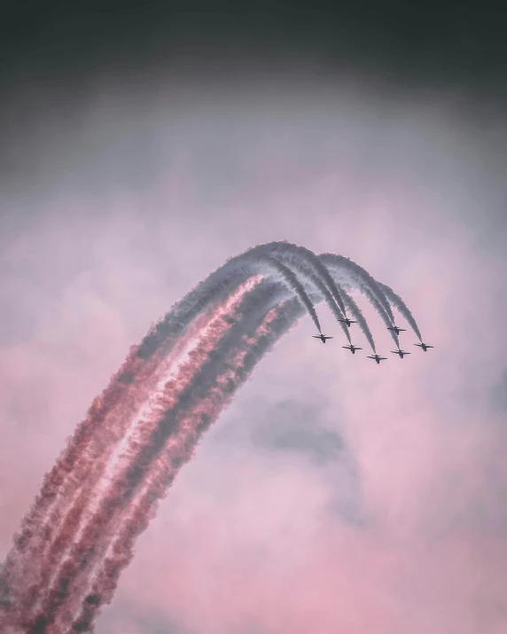 a group of airplanes flying through a cloudy sky, by Emma Andijewska, pexels contest winner, aestheticism, pink arches, military parade, profile picture, with red haze