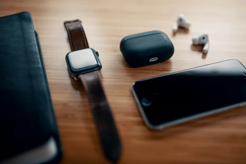 a cell phone sitting on top of a wooden table, airpods, wearing leather, creterion collection, thumbnail