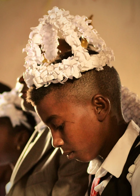 a group of young men standing next to each other, an album cover, by Ingrida Kadaka, trending on unsplash, afrofuturism, intricate detailed tiara, in church, madagascar, young boy