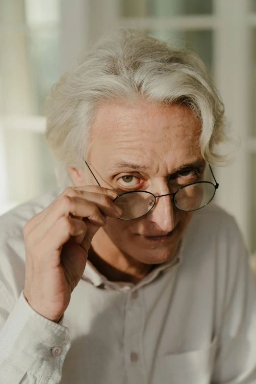 a man sitting at a table in front of a laptop computer, by Andrew Geddes, photorealism, flowy white grey hair, wim wenders, promo image, a very macular woman in white