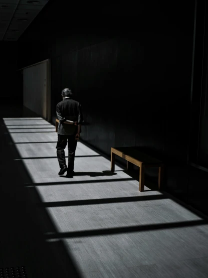 a man walking down a dark hallway next to a bench, shadowing, instagram post, shot with sony alpha, philosopher