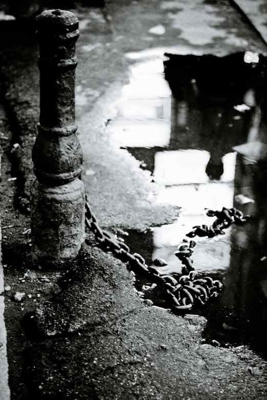 a black and white photo of a fire hydrant, inspired by Sergio Larraín, chains, rainy; 90's photograph, 1990 photograph, streets of calcutta