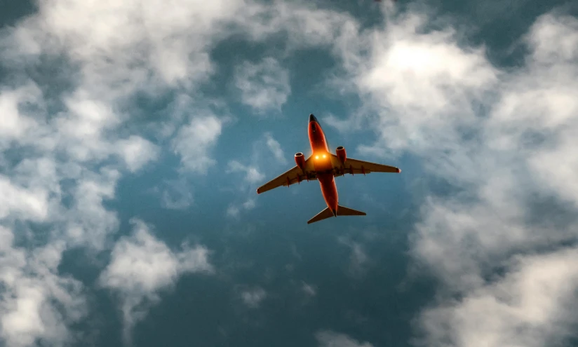 a large jetliner flying through a cloudy blue sky, by Carey Morris, pexels contest winner, red sprites in the atmosphere, bottom angle, 1 2 9 7, a wooden