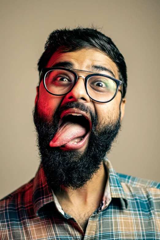 a man with glasses and a beard sticking out his tongue, trending on pexels, hyperrealism, provocative indian, fleshy creature above her mouth, lgbtq, square masculine jaw
