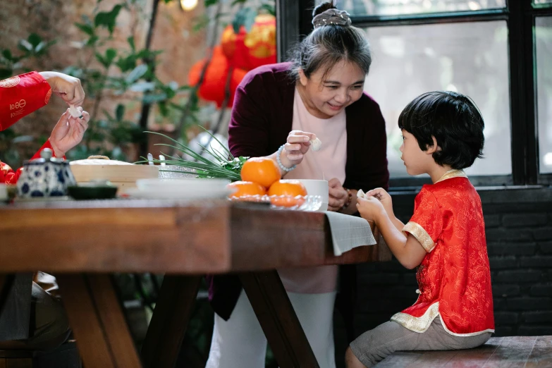 a woman and a child sitting at a table, inspired by Cui Bai, pexels contest winner, holiday season, manuka, asian man, ready to eat