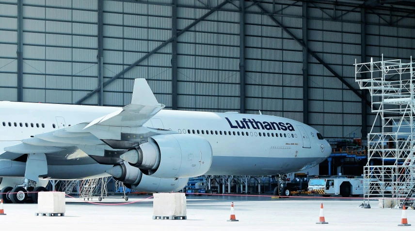 a large jetliner sitting inside of a hangar, a cartoon, unsplash, renaissance, 🚿🗝📝, ”ultra realistic, landing gear, thiago lehmann