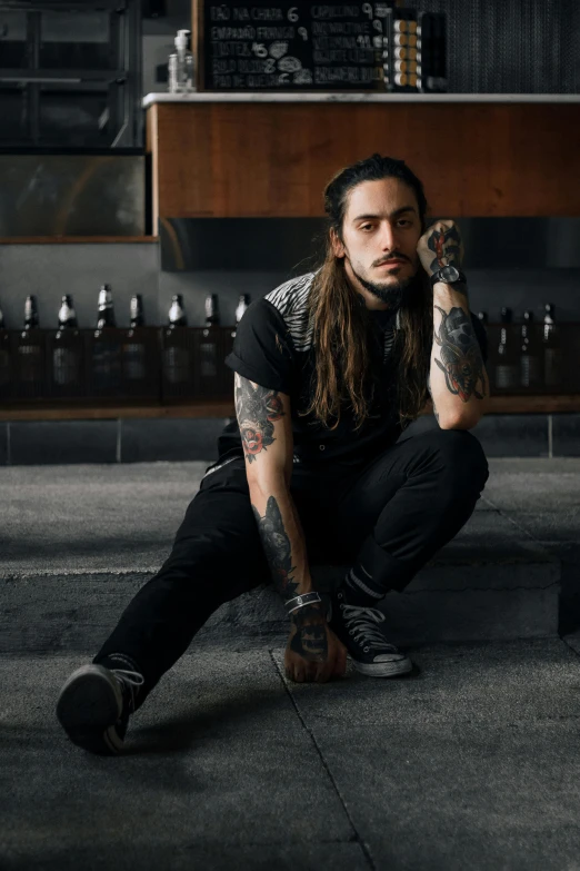 a man with long hair sitting on the floor, a tattoo, inspired by Jeremy Henderson, pexels contest winner, sitting at a bar, avatar image, headshot photo, asher duran