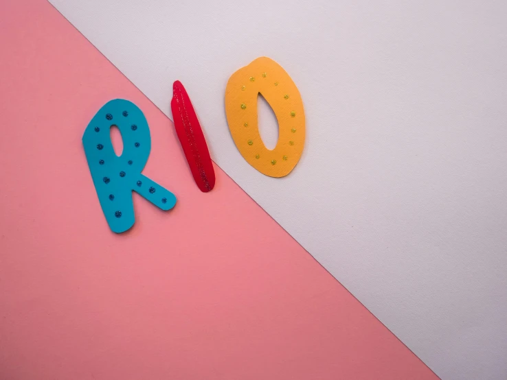 the word rio spelled in plastic letters on a pink and white background, an album cover, trending on unsplash, whiteboards, red and teal and yellow, red iron oxide, rainbow coloured rockets