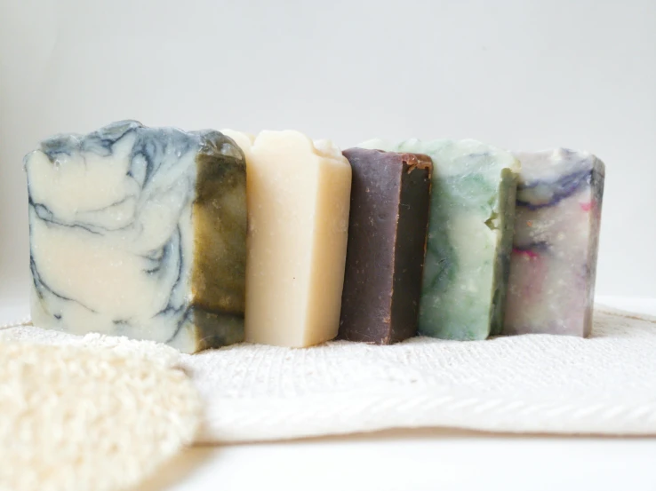 a group of soap bars sitting on top of a towel, by Helen Stevenson, on a pale background, pale ivory skin, thumbnail, angled