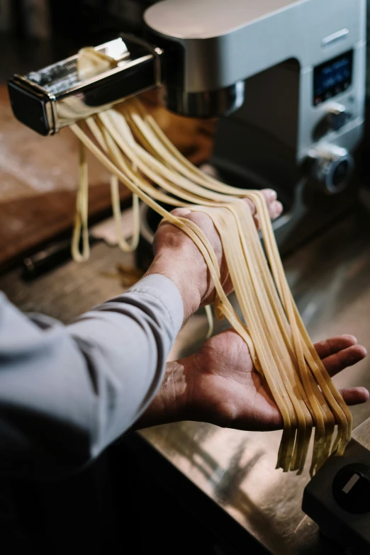 a man that is holding some noodles in his hand, pexels contest winner, process art, vsco film grain, loom, bending down slightly, ribbon
