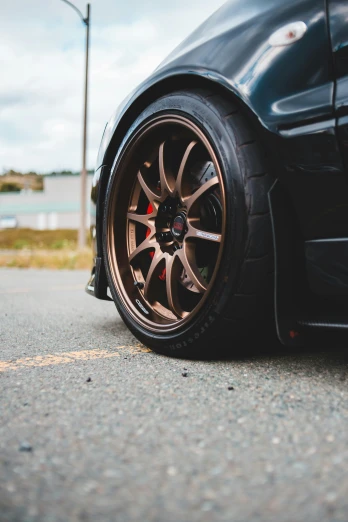 a black car parked on the side of the road, detailed alloy wheels, rose gold, jdm, viral image