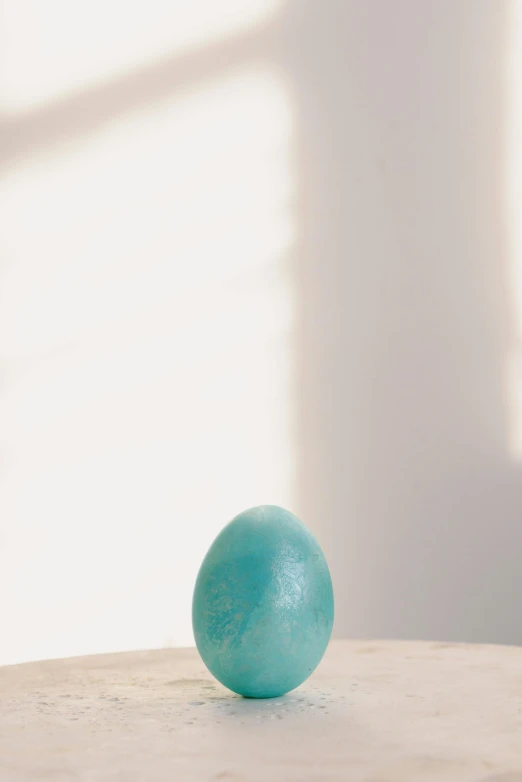 a blue ball sitting on top of a wooden table, a marble sculpture, easter, shot for pottery magazine, teal skin, {on edge}