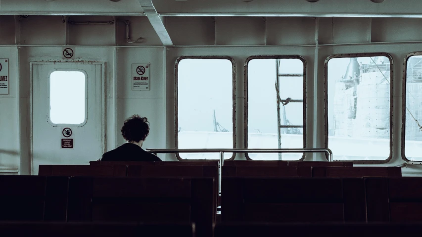 a person sitting on a train looking out the window, inspired by Elsa Bleda, pexels contest winner, serial art, standing on a ship deck, interior of staten island ferry, a cold, photo of the middle of the ocean