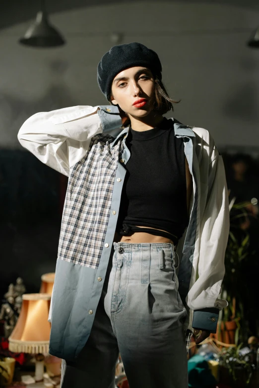 a woman standing in a room next to a lamp, trending on pexels, she is wearing streetwear, flannel, mixed materials, portrait androgynous girl