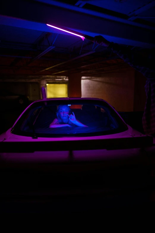 a car that is sitting in a garage, a portrait, inspired by Nan Goldin, conceptual art, purple lights, ap news photograph, matt wisniewski, inside a gang hideout