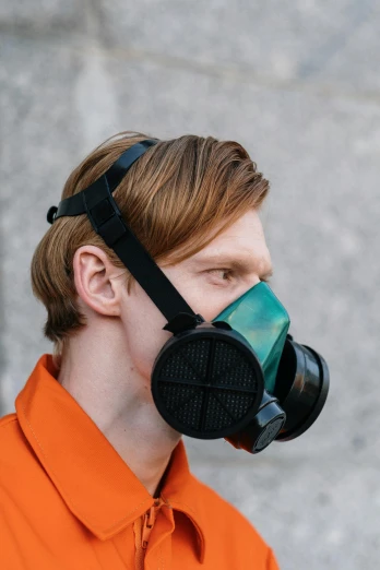 a man in an orange shirt wearing a gas mask, reddit, renaissance, green and black colors, official product photo, sustainable materials, made of rubber