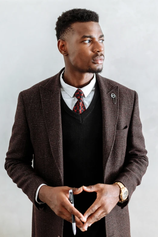 a man in a suit and tie making a heart with his hands, a portrait, inspired by Theo Constanté, trending on pexels, brown sweater, mkbhd as iron man, professional profile photo, wearing fashion suit