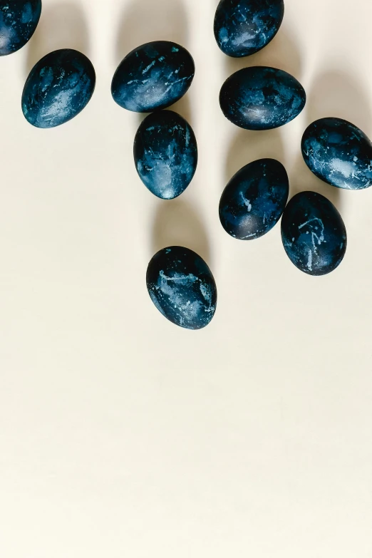 a group of blue eggs sitting on top of a white table, an album cover, by Matthias Stom, trending on unsplash, translucent grapes closeup, carved from sapphire stone, indigo and venetian red, profile image