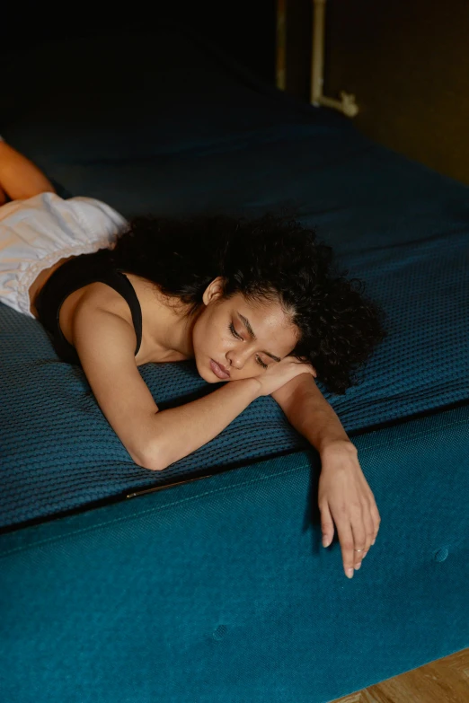 a woman laying on top of a blue mattress, inspired by Nan Goldin, trending on pexels, renaissance, mixed-race woman, looking tired, high quality photo, neri oxman
